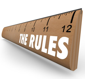 A wooden ruler with the words The Rules to represent laws, regulations, limits or guidelines meant to tell you what is allowable or forbidden behavior or activity